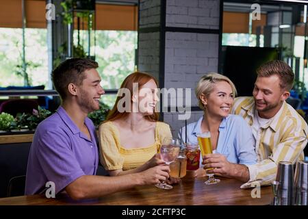 Schöne kaukasische Männer und Frauen halten freundliche Treffen im Café, sie haben eine tolle Zeit nach der Arbeit, haben Gespräch. Freizeit, Getränke, Menschen und communicati Stockfoto
