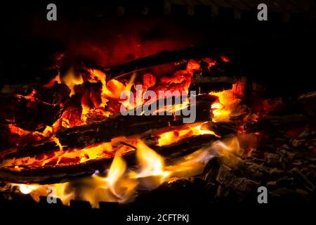 Rote Kohlen mit Feuer auf schwarzem Hintergrund. Brennende Kohlen und Holz im Feuer. Brennendes Holz, um warm und warm zu halten. Glühende Glut in glühendem Rot, orange Farbe. Stockfoto