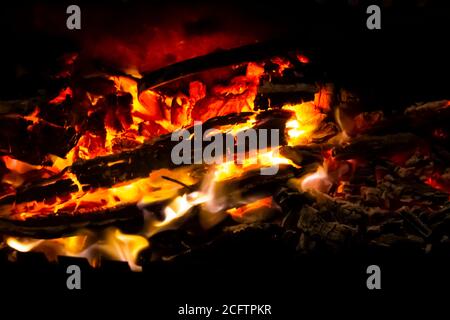 Rote Kohlen mit Feuer auf schwarzem Hintergrund. Brennende Kohlen und Holz im Feuer. Brennendes Holz, um warm und warm zu halten. Glühende Glut in glühendem Rot, orange Farbe. Stockfoto
