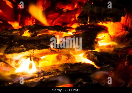 Rote Kohlen mit Feuer auf schwarzem Hintergrund. Brennende Kohlen und Holz im Feuer. Brennendes Holz, um warm und warm zu halten. Glühende Glut in glühendem Rot, orange Farbe. Stockfoto