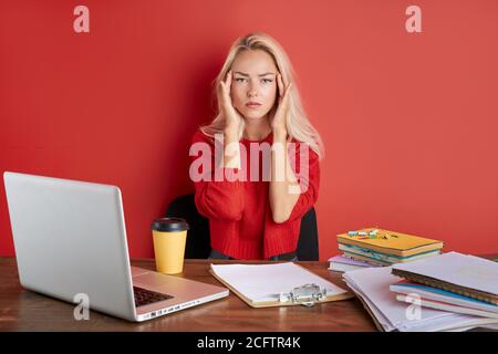 Junge betont kaukasische Frau arbeitet mit Computer-Laptop in Frustration, Depression. Sie hat Stress-Probleme und Verzweiflung bei der Arbeit, isoliert auf rot Stockfoto