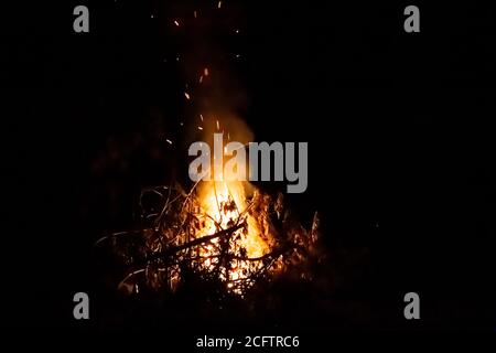 Feuer auf einem dunklen Hintergrund. Feuer aus Feuerholz aus der Nähe. Brennende Funken aus der Nähe, Brandmuster. Rot und orange Infernal Glut des Feuers in der da Stockfoto