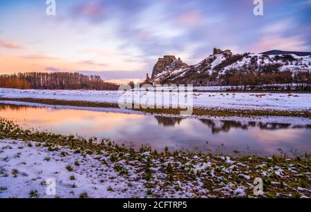 Schneebedeckte Ruinen der Burg Devin über der Donau in Bratislava, Slowakei bei Sonnenaufgang Stockfoto