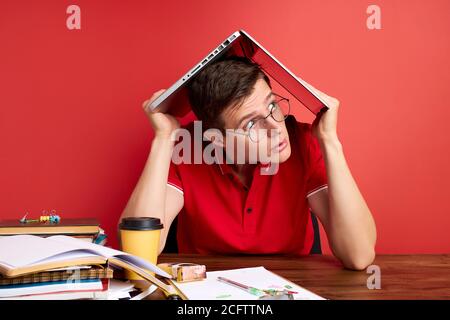 Deprimiert männlich entlassen von Job bei der Arbeit aufgrund der Wirtschaftskrise und Rezession, Laptop über den Kopf halten, weiß nicht, wie man alle prodl zu lösen Stockfoto