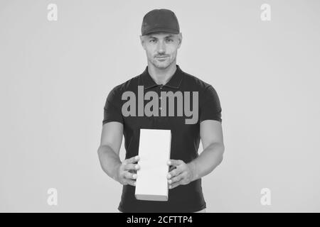 Service plus Qualität. Serious Kerl halten Paket gelben Hintergrund. Man Lieferservice. Express-Kurierdienst. Versand- und Lieferservice. Versand per Paketpost. Wert auf uns verlassen, kopieren Raum. Stockfoto