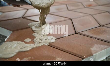 Füllen von Pflasterplatten mit einer Lösung auf der Straße. Der Bauherr füllt die Nähte zwischen den Pflasterplatten. Stockfoto
