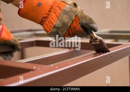 Hand des Auftragnehmers mit Pinsel, die Metallkonstruktion lackieren. Stockfoto