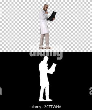 Junger männlicher Arzt, der beim Gehen eine MRT-Hirnuntersuchung liest und überprüft, Alpha-Kanal Stockfoto