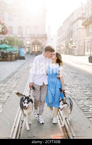 Paar in der Liebe mit Husky Hunde, küssen und zu Fuß auf der City Street. Schöne Aussicht auf die alte europäische Stadt, Sommer sonnigen Tag und alte Gebäude auf der Stockfoto