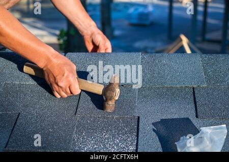 Dachdecker Installation Ecke Bitumen Dach Schindeln mit Hammer und Nägel. Stockfoto