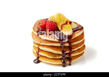 Stapel von Pfannkuchen mit Banane, Himbeeren und Schokoladensirup auf weiß Stockfoto