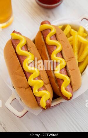Hausgemachter Senf Hot Dog mit Pommes auf weißem Holzhintergrund, Hochwinkel-Ansicht. Stockfoto