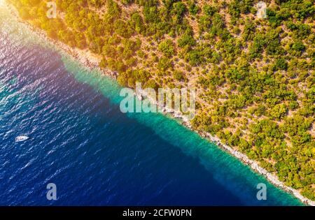 Küstengebiet mit blauem klarem Wasser und Wald an Land, Luftaufnahme mit Drohne. Halb Land halb Meer auf einer diagonalen Linie. Ein malerischer Ort, wo tr Stockfoto