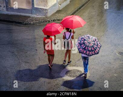 SANTIAGO DE CUBA, KUBA - CA. JANUAR 2020: Fußgänger, die an einem regnerischen Tag in Santiago de Cuba spazieren. Stockfoto