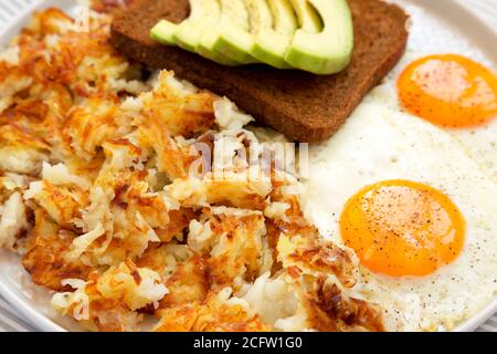 Leckere hausgemachte gebratene Hashbrowns und Eier auf einem Teller, Blick aus der unteren Ecke. Nahaufnahme. Stockfoto