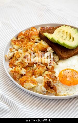 Leckere hausgemachte gebratene Hashbrowns und Eier auf einem Teller, Seitenansicht. Stockfoto