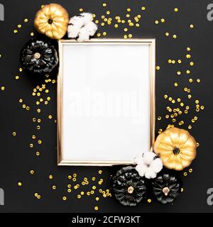 Goldrahmen verziert mit schwarzem und goldenem Halloween Kürbis und Lametta mit Platz für Text. Isoliert auf schwarzem Hintergrund. Flach liegend, Draufsicht. Stockfoto