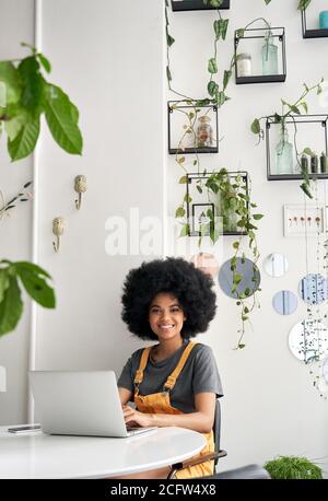 Glückliche afrikanische Dame Student mit Laptop sitzen am Tisch im Café Blick auf Kamera. Stockfoto