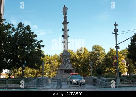 Statue von Columbus im Columbus Circle, bewacht von der Polizei der NYPD Autos und umgeben von Barrikaden, um Schäden aus jüngster Zeit zu verhindern Proteste Stockfoto