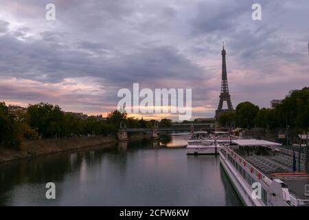 Paris, Frankreich. September 05. 2020.Sonnenaufgang oder Sonnenuntergang hinter dem eiffelturm. Blick auf die seine mit einem Restaurantboot im Vordergrund. Metallbrücke. Stockfoto