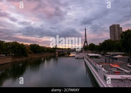 Paris, Frankreich. September 05. 2020.Sonnenaufgang oder Sonnenuntergang hinter dem eiffelturm. Blick auf die seine mit einem Restaurantboot im Vordergrund. Metallbrücke. Stockfoto