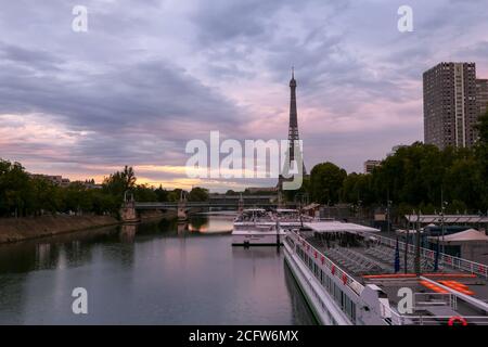 Paris, Frankreich. September 05. 2020.Sonnenaufgang oder Sonnenuntergang hinter dem eiffelturm. Blick auf die seine mit einem Restaurantboot im Vordergrund. Metallbrücke. Stockfoto