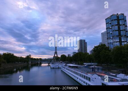 Paris, Frankreich. September 05. 2020.Sonnenaufgang oder Sonnenuntergang hinter dem eiffelturm. Blick auf die seine mit einem Restaurantboot im Vordergrund. Metallbrücke. Stockfoto