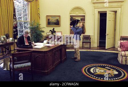 12/24/1994 - Foto von Chelsea Clinton Spielen mit Socken die Katze im Oval Office, während Präsident William Jefferson Clinton arbeitet an seinem Schreibtisch Stockfoto