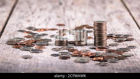 Stapel von Vierteln auf einem alten Holztisch inmitten verstreut Coins / Investment Growth Concept Stockfoto