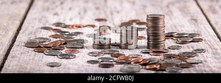 Stapel von Vierteln auf einem alten Holztisch inmitten verstreut Coins / Investment Growth Concept Stockfoto