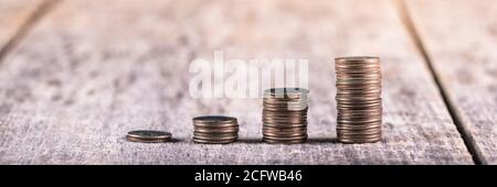 Stapel von Quartieren auf einem alten Holztisch / Investition Wachstumskonzept Stockfoto