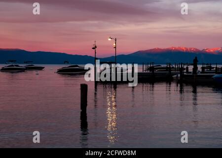 Später Sonnenuntergang am Lake Tahoe, Licht reflektiert auf den Bergen dahinter, Boote und Menschen in Silhouette Stockfoto