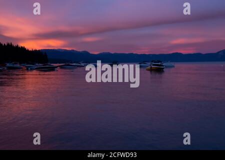 Wunderschöner tiefer Sonnenuntergang in rosa lila und blau, Lake Tahoe, Tahoe City, Boote und Berge im Hintergrund Stockfoto