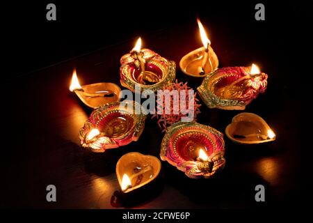 Bunte Diwali Öllampen, Deepavali Öllampen in schöner Formation mit Blumen in der Mitte beleuchtet. Stockfoto