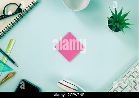 Rosa Haftnotiz oder Notizblock und Bürobedarf als Tastatur, Stift, Bleistift, Büropflanzen, Notebook, Brille, Smartphone, Kopfhörer, Kaffeetasse auf moderne sauber Stockfoto