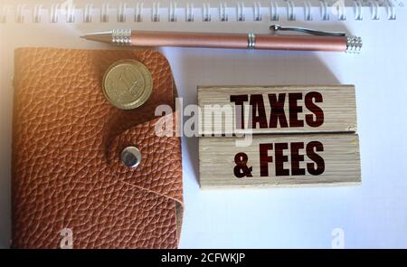 Steuern und Gebühren Text auf Holzblöcke, Brieftasche und Münzen. Geschäftskonzept Stockfoto