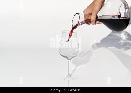 Sommelier gießt Rotwein von Dekanter bis Weinglas auf weißen Hintergrund. Stockfoto