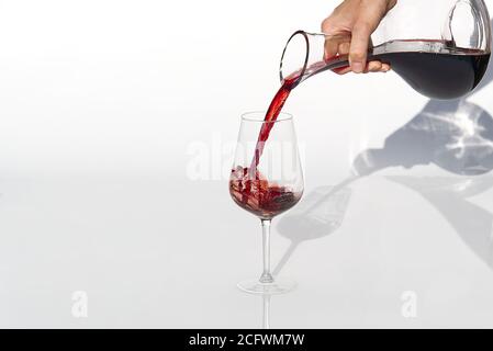 Sommelier gießt Rotwein von Dekanter bis Weinglas auf weißen Hintergrund. Stockfoto