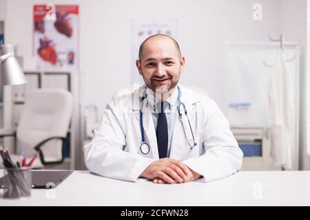 Porträt eines jungen Arztes lächelnd Blick auf die Kamera im Krankenhaus Büro tragen weißen Mantel und Stethoskop. Stockfoto
