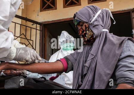 Lhokseumawe, Indonesien. September 2020. Medizinische Offiziere in Schutzanzügen (PSA) untersuchen einen ethnischen Rohingya-Bewohner, der eine Gesichtsmask in einem provisorischen Unterschlupf trägt.Fast 300 ethnische Rohingya-Muslime sind in den Gewässern des Aceh-Meeres gestrandet. Bestehend aus Erwachsenen und Kindern, die aufgrund von Austrocknung und Hunger schwach sind, nachdem sie auf hoher See beeinflusst wurden. Kredit: SOPA Images Limited/Alamy Live Nachrichten Stockfoto