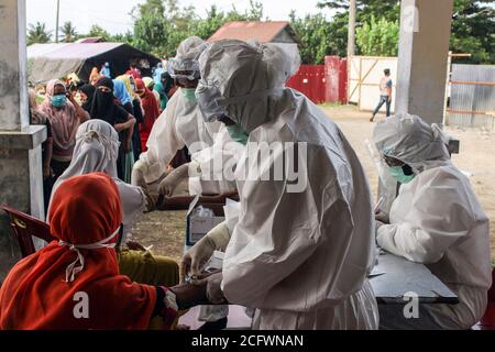 Lhokseumawe, Indonesien. September 2020. Medizinische Offiziere in Schutzanzügen (PSA) nehmen Blut ab, um ethnische Rohingya-Flüchtlinge in einem provisorischen Unterschlupf zu untersuchen.Fast 300 ethnische Rohingya-Muslime waren in den Gewässern des Aceh-Meeres gestrandet. Bestehend aus Erwachsenen und Kindern, die aufgrund von Austrocknung und Hunger schwach sind, nachdem sie auf hoher See beeinflusst wurden. Kredit: SOPA Images Limited/Alamy Live Nachrichten Stockfoto