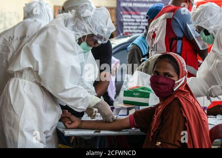 Lhokseumawe, Indonesien. September 2020. Ein Polizist in Schutzanzügen (PSA) untersucht eine Rohingya-Ethnin in einem provisorischen Tierheim.Fast 300 ethnische Rohingya-Muslime sind in den Gewässern des Aceh-Meeres gestrandet. Bestehend aus Erwachsenen und Kindern, die aufgrund von Austrocknung und Hunger schwach sind, nachdem sie auf hoher See beeinflusst wurden. Kredit: SOPA Images Limited/Alamy Live Nachrichten Stockfoto