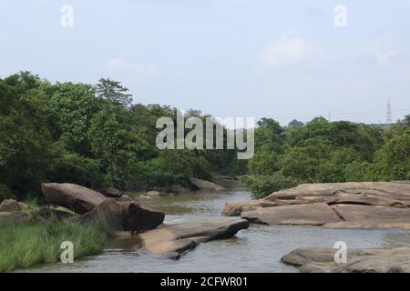 Bokeh-Aufnahme eines fließenden Wasserfalls mit selektivem Fokus und Baumhintergrund. Kleine Kinder baden im gefährlichen Wasserfall in Mirzapur, Indien w Stockfoto