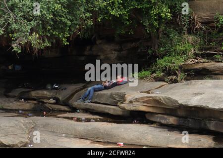 Bokeh-Aufnahme eines fließenden Wasserfalls mit selektivem Fokus und Baumhintergrund. Kleine Kinder baden im gefährlichen Wasserfall in Mirzapur, Indien w Stockfoto