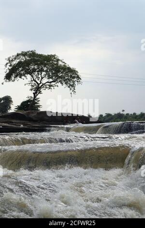 Bokeh-Aufnahme eines fließenden Wasserfalls mit selektivem Fokus und Baumhintergrund. Kleine Kinder baden im gefährlichen Wasserfall in Mirzapur, Indien w Stockfoto
