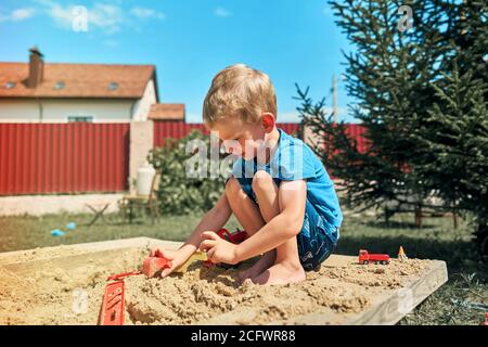 Niedliche Babyjungen spielen mit Sand in einer sandbox Stockfoto