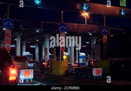 Autotransport auf mehrspurigen Autobahn Straße und Mautentor, Drohne Antenne Draufsicht in der Nacht. Pendlerverkehr, City Life Konz Stockfoto