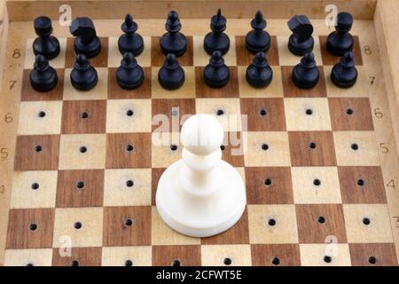 Konzept, kleine schwarze Holzschachfiguren stehen vor dem großen weißen Bauer Stockfoto