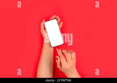 Mockup Bild der Frau Hand hält Handy mit weißem leeren Bildschirm auf hellrotem Hintergrund - Online-Shopping oder Online-Bildung Konzept, sele Stockfoto