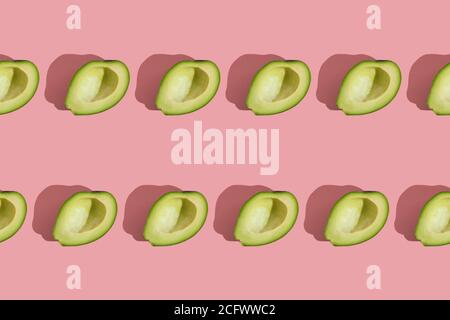 Trending Stil Muster der Hälfte seedless grün Avocado auf rosa Hintergrund mit hartem Licht. Kreative Lebensmitteltextur Stockfoto